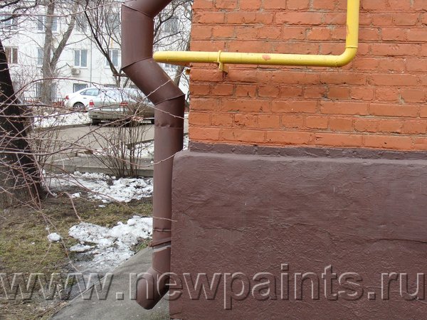 Ржавая водопроводная труба и цоколь жилого дома, окрашенные Резиновой краской. Газовая труба окрашена желтой Резиновой краской.